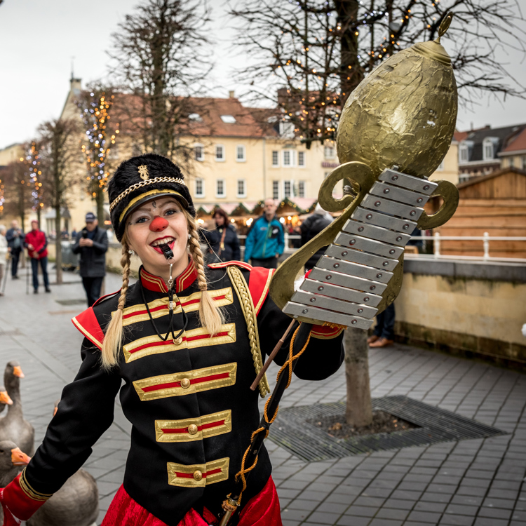 Vrouw en man in zwart rood fanfarepakje en rode neus met daartussen paraderende ganzen