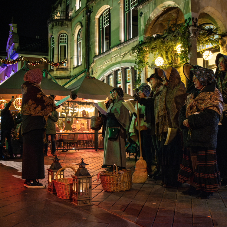 Koor in Dickenskostuums zingen in de avond